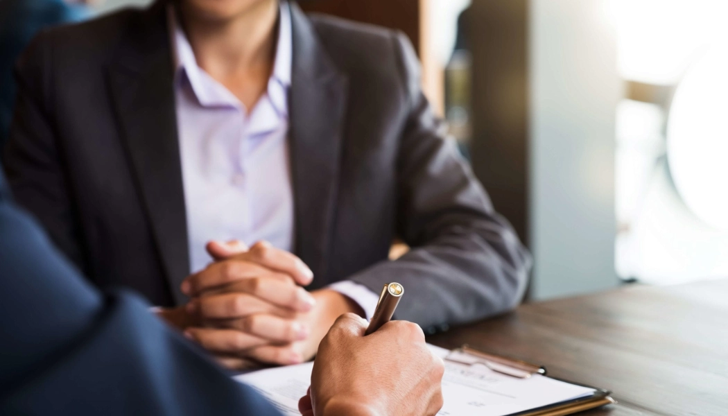 два человека общаются за столом, один делает заметки, лиц не видно