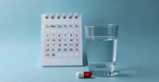 Alimatravir: таблетка и стакан воды на фоне открытого календаря
